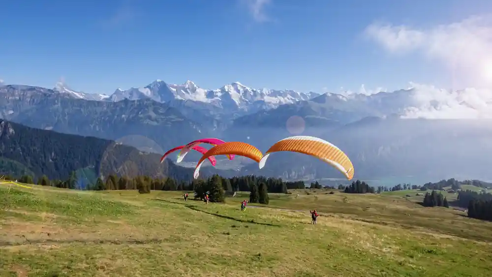 Two orange wings inflating on the launch meadow above the lake